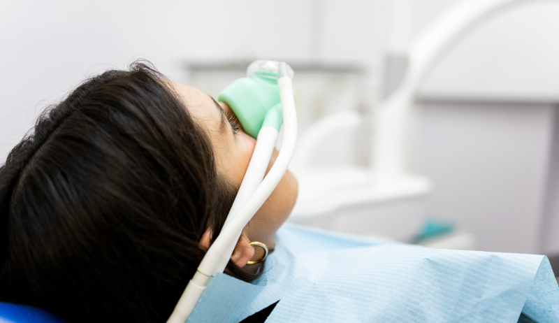Patientin liegt im Behandlungsstuhl und erhält Lachgas über eine Nasenmaske zur entspannteren Zahnbehandlung